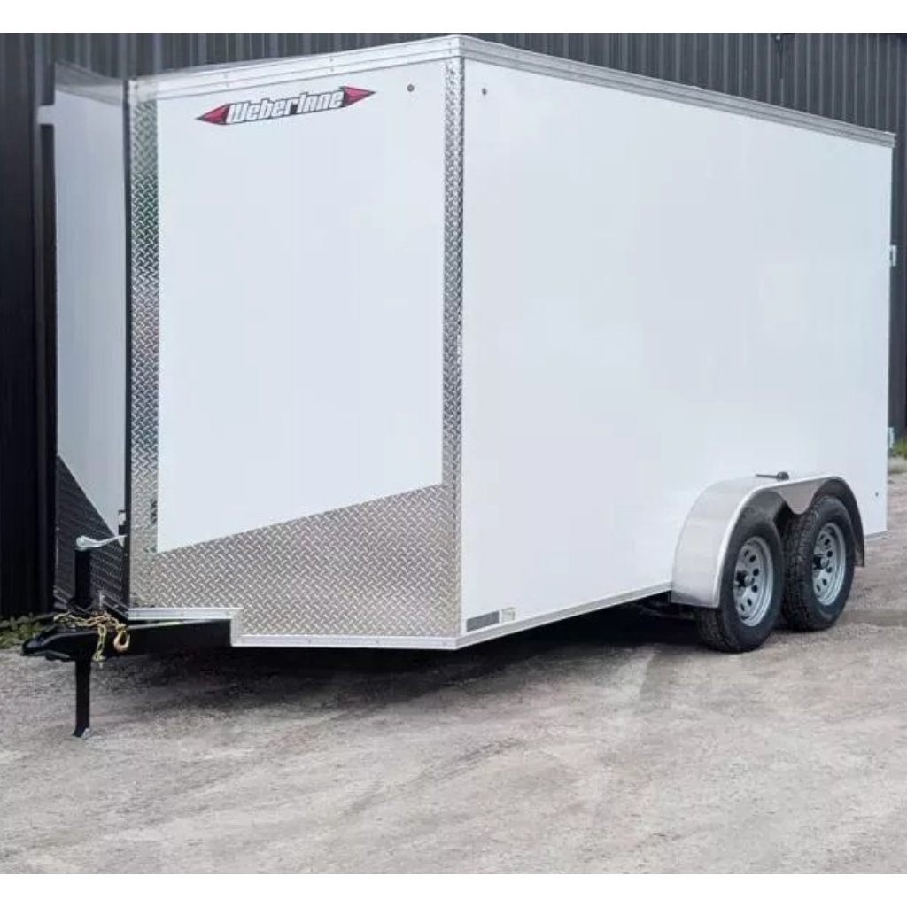 2026 WEBERLANE 7X14 Estate Series white enclosed tandem axle trailer with 12" extra height and ramp door, featuring diamond plate trim, is parked on gravel next to a black building.