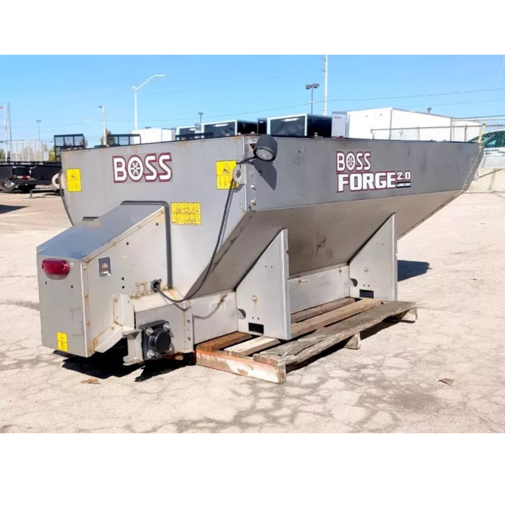 USEDVBS 294042 BOSS FORGE 2 cu yard stainless steel salter with yellow warning labels, positioned on a wooden pallet outdoors.