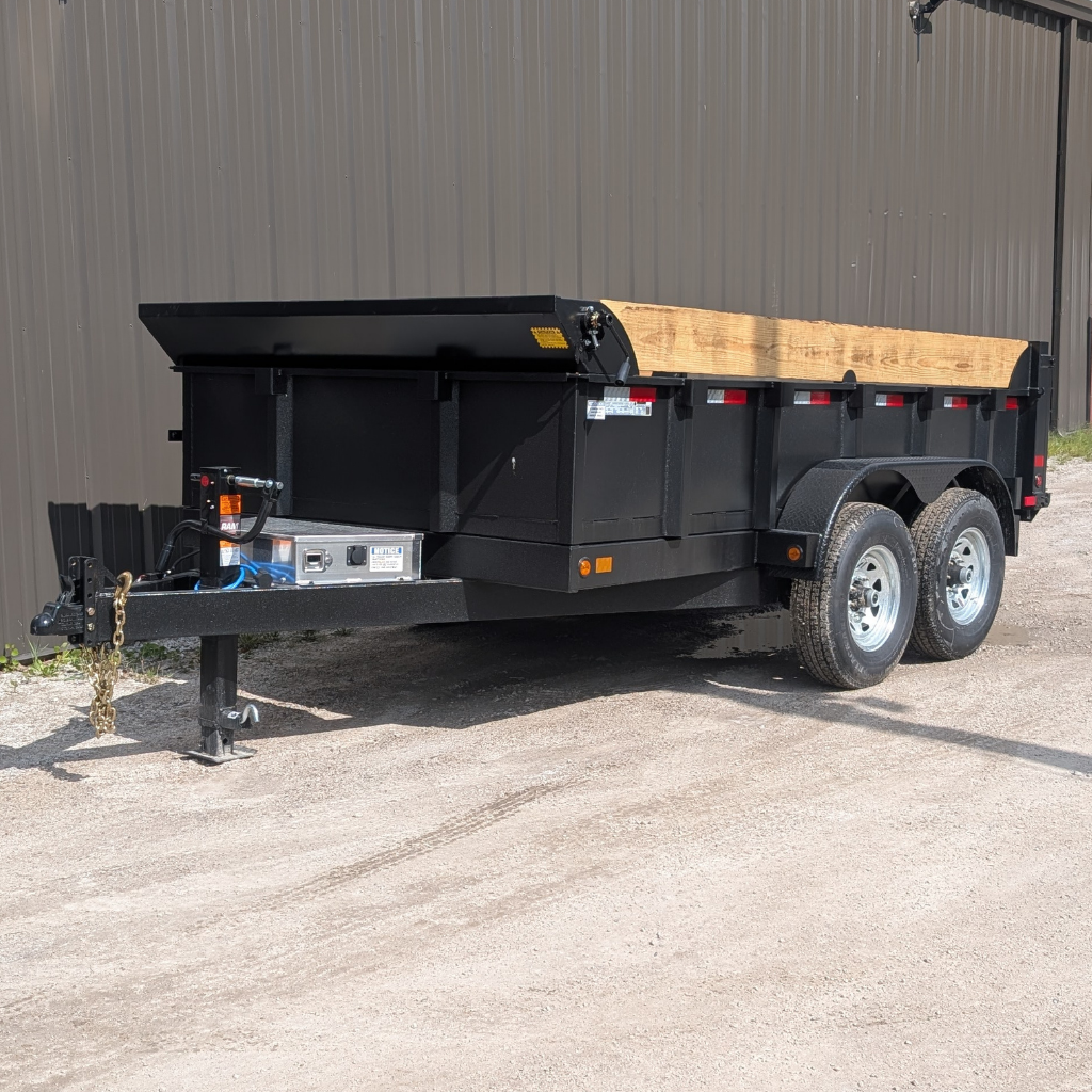 2026 CANADA TRAILER 83X12 DUMP 14000 GVWR dual-axle trailer with wooden side rails parked on gravel near a metal building.