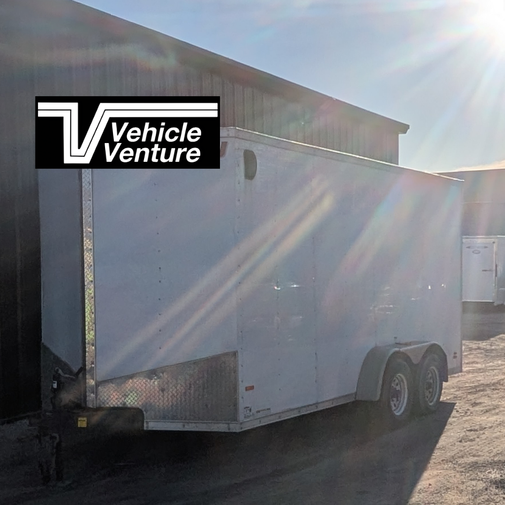 A USED - 2017 MTI 7X16 Enclosed Trailer with ramp door in white is parked outside a building in sunlight, with a Vehicle Venture logo in the top left corner.