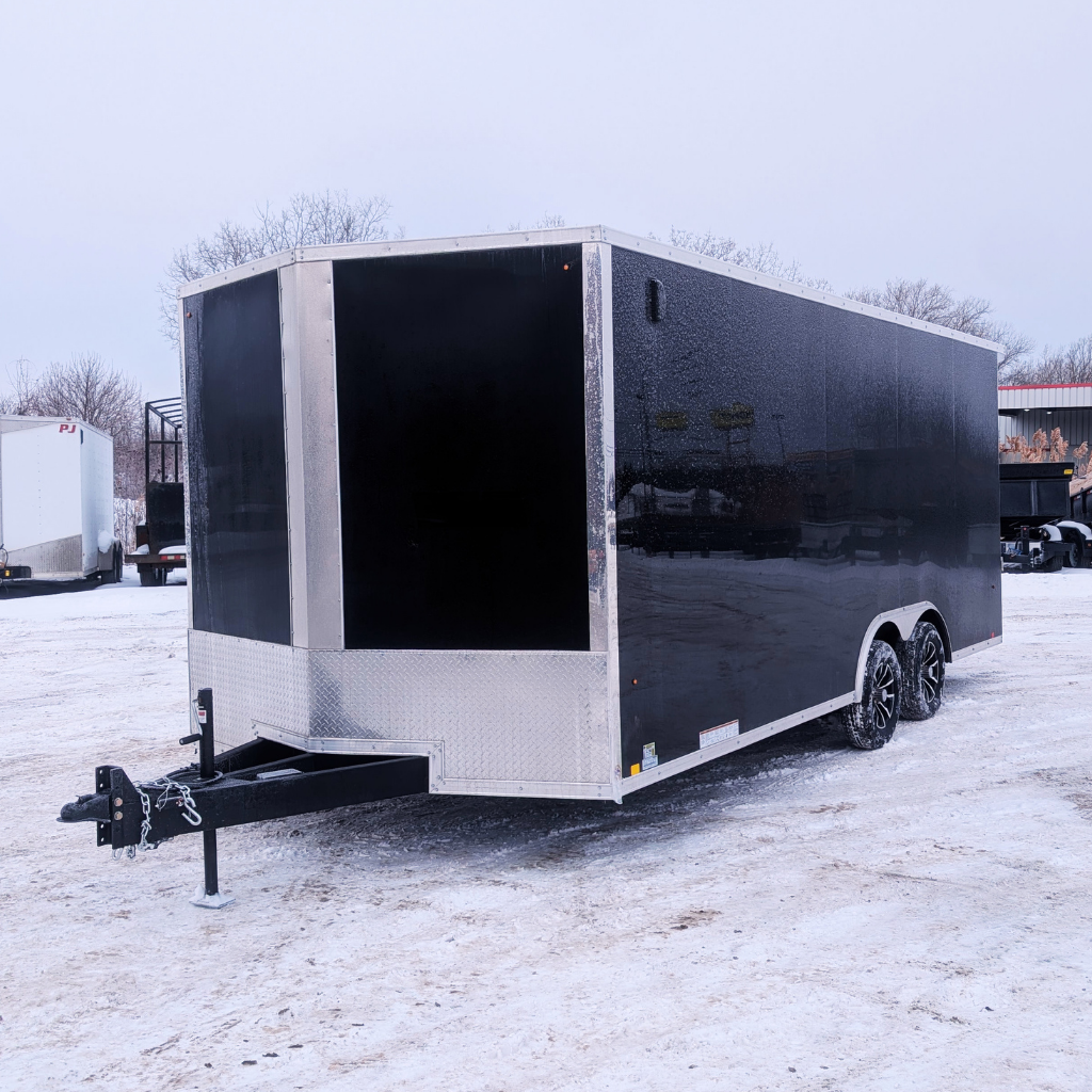 A 2026 Pace 8.5X20 DLX Outback Flat Top utility trailer with a ramp door, 12" extra height, and dual axles in black is parked on snowy ground in an outdoor lot.